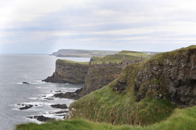 towering cliffs dropping off preciptuously into the sea, castle ruins in the distance