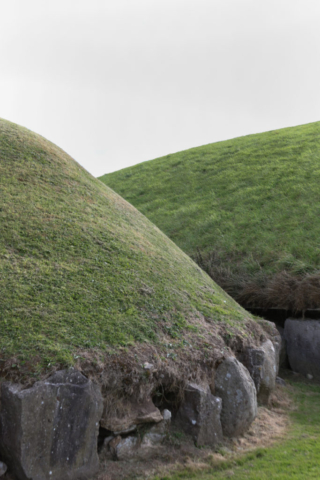 Two grass topped burial mounds ringed by boulders