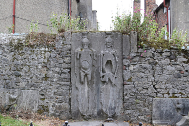 Grave stone carved pair of tall skeletons