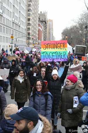 Young woman holding rainbow sign Stronger Together