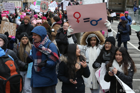 Young group of women one holding sign Female equals Male