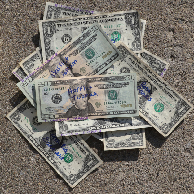 pile of one dollar bills with harriet tubman twenty on top