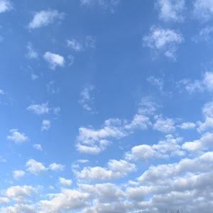 puffy clouds in lower left thinning out to deep blue sky