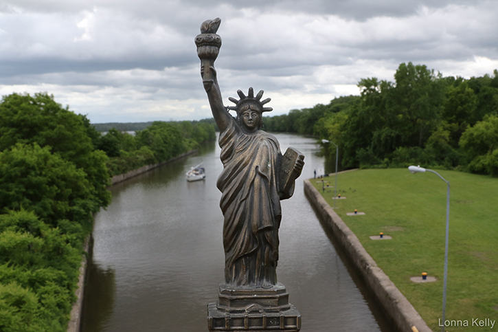 statue of liberty above the Erie Canal Lock 7 a boar approaches behind her