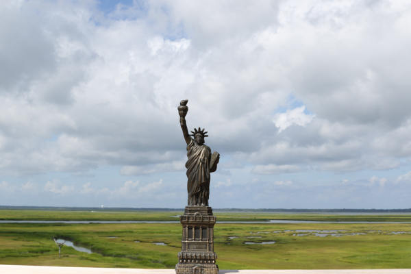 statue of libert with salt marsh and white clouds in background