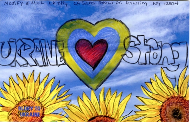 Multi layered red, blue, yellow heart with text Ukraine Strong  in blue sky over yellow sunflowers