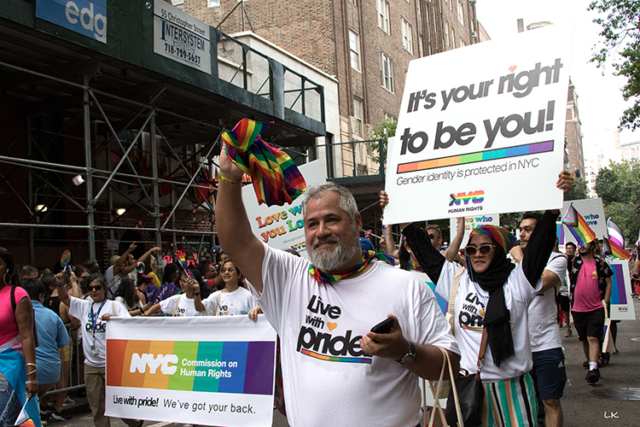 marchers with white tee shirts Live with Pride and poster It's your right to be you gender identity is protected in NYC