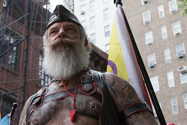 Shot from low angle older person with full beard and mustache barechested wit tattoos and nipple rings