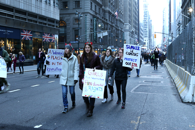 grouop of four women walking on NY avenue holding protest signs A womans place is in the revolution