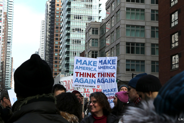 crowd in street large building sign held about Make American Great Again - my 12 year old niece