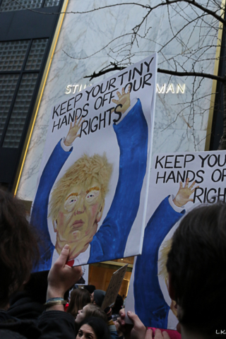 Protest sign caricature of trump with words Keep your tiny hands off our rights