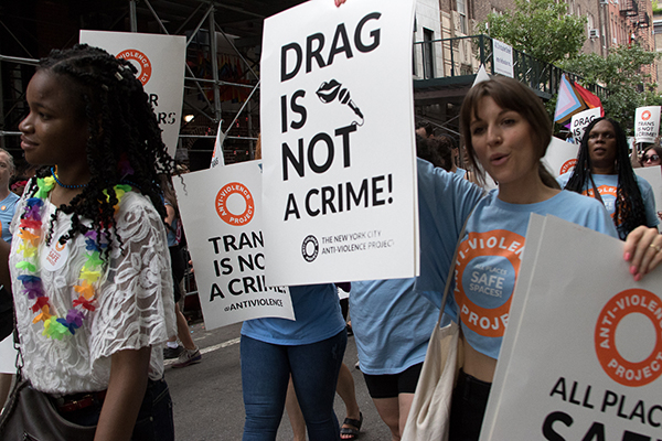 Person in blue tee shirt with sign Drag is NOT a crime