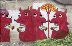 foure red devils with googly eyes dded to line drawing on cement bridge under RR track of four heads with open mouths big nose