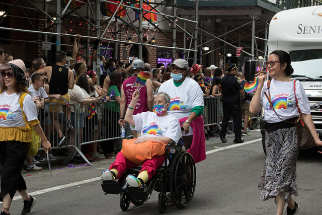 Marcher using wheelchair in pride shirt pushed by marcher in pride shirt