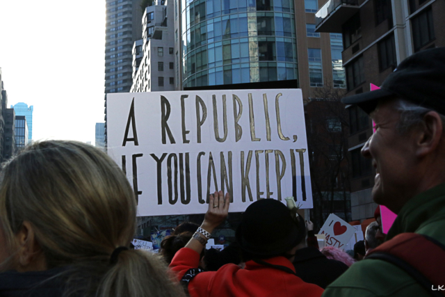 woman holding sign above crowd reads a republic if you can keep it