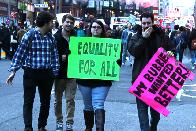 foru young adults two protest signs Equality for all and My Bubbie Wanted Better