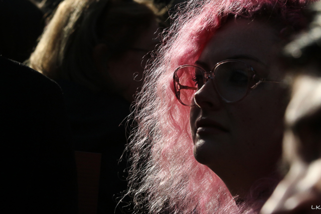 semi profile of woman with pink hair illuminated and profile outlined in light