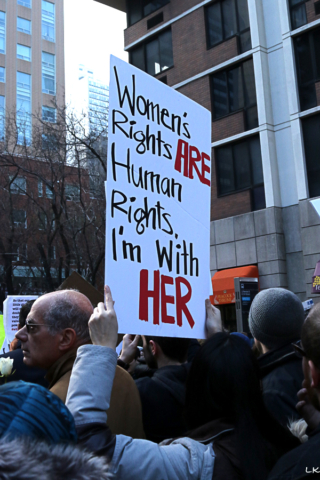 crowd from bach woman holds sign Womens rights are human rights I'm with her