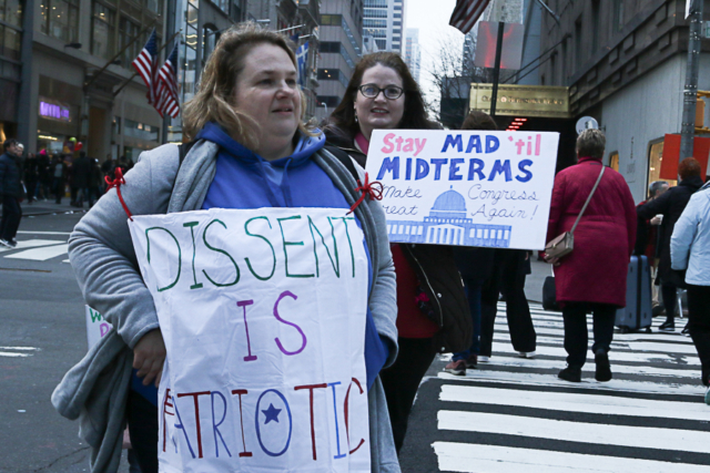 two women one wears sign dissent is patriotic other holds one stay mad til midterum make congress great again