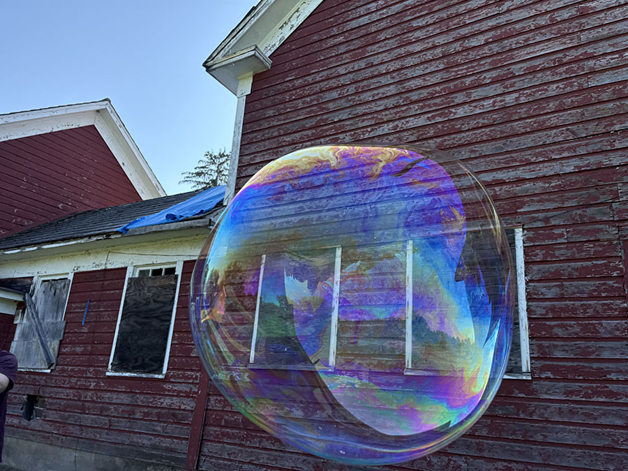 iridescencent orb floats by red barn badly in need of paint