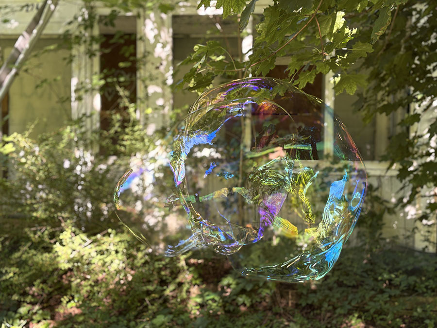 iridescent orb floats by abandoned house 